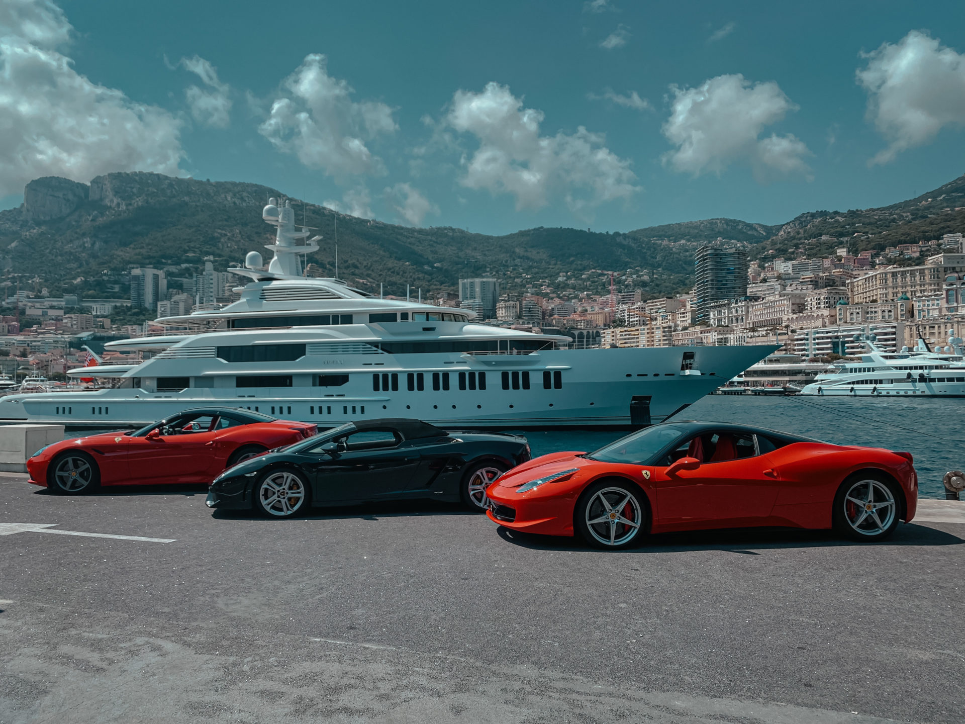 Ferraris beside a superyacht in the Port of Monaco